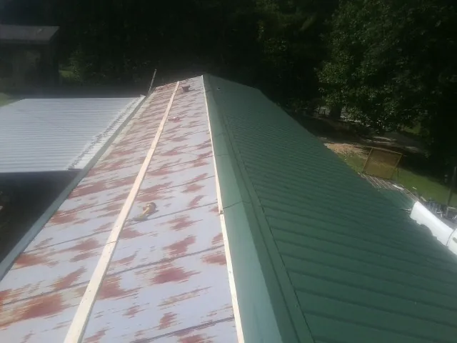 Old rusted panels beside newly installed green metal roofing — Wind Damage Roof Repair by Roofing Brothers in Elk Creek